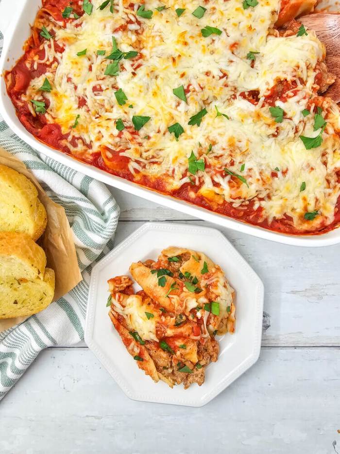 stuffed shells recipein casserole dish and plated, garlic bread on the side