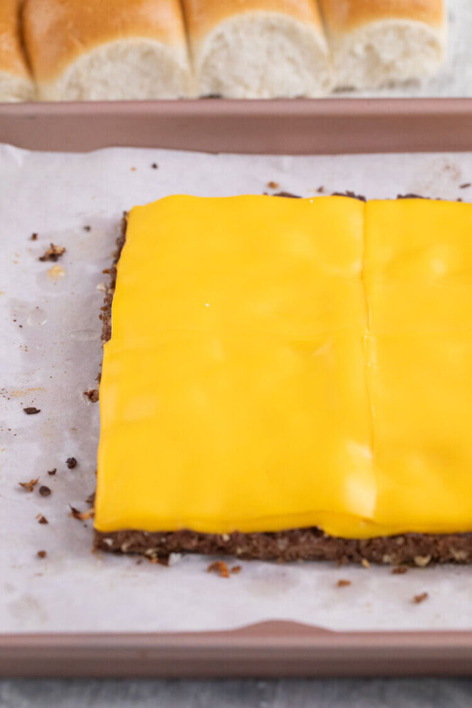 Baked meat on a pan topped with melted cheese for White Castle Burger Copycat Recipe.
