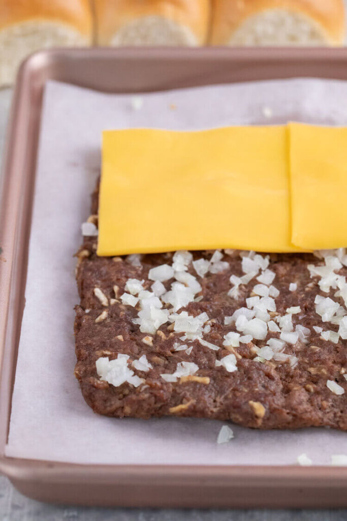 Meat on a pan topped with sliced cheese for White Castle Burger Copycat Recipe.
