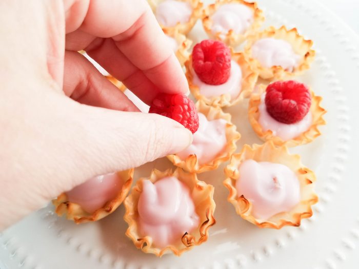putting raspberries in tarts
