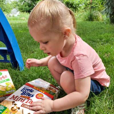 little girl in the grass with a box of Little Bites® Mini Tarts