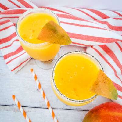 sky view of mango margarita with orange towel and straws