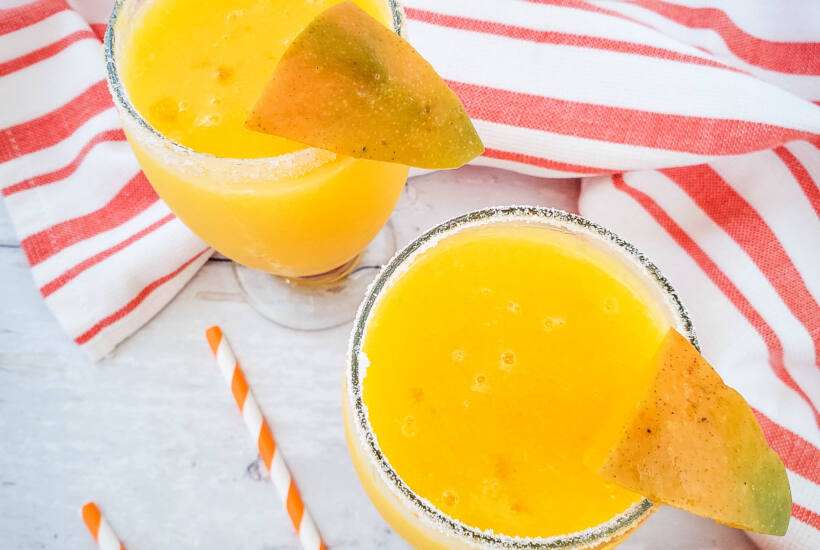 sky view of mango margarita with orange towel and straws