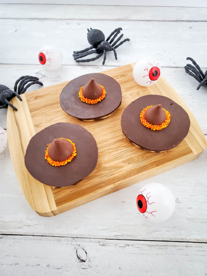 witch hat cookies with spiders on a wood block