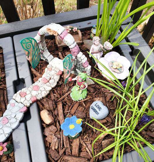 fairies and decorations in a garden planter with mulch
