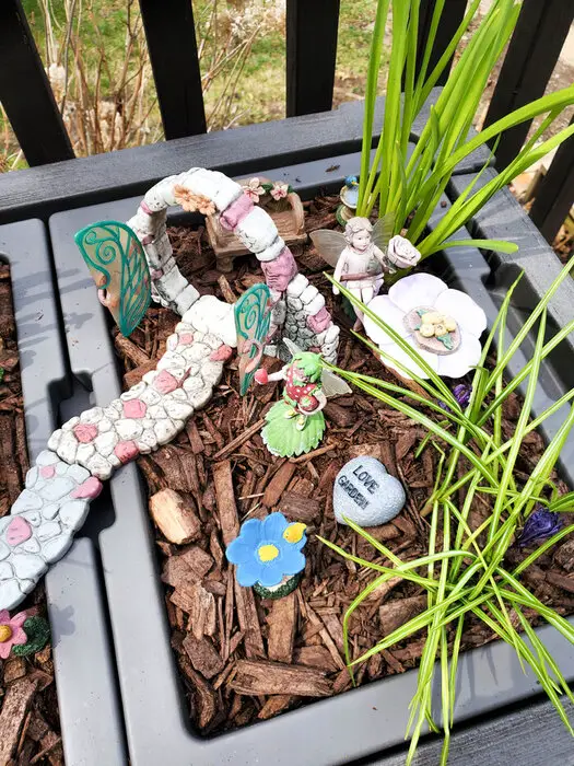 fairies and decorations in a garden planter with mulch