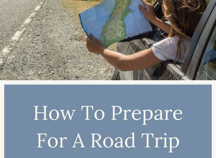 person holding map out a car window on the side of the road with mountains in the distance