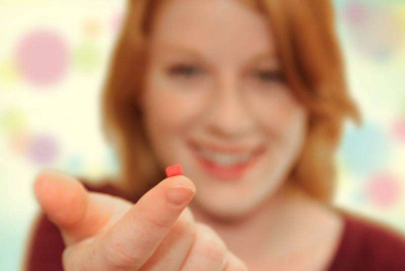 woman with tiny pill on finger