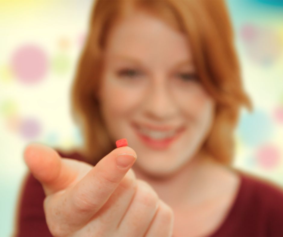 woman with tiny pill on finger