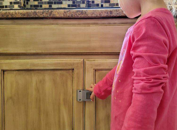 child touching sink cabinet with Door Guardian lock on it