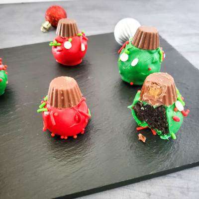 oreo christmas ornaments on a black tray. One has a bite out it