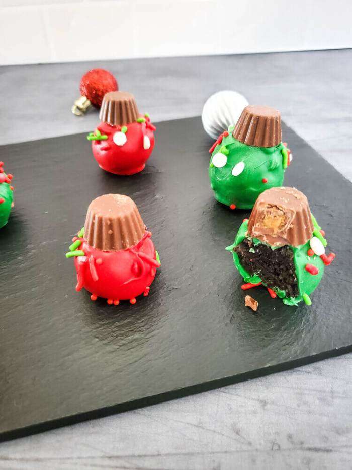 oreo christmas ornaments on a black tray. One has a bite out it