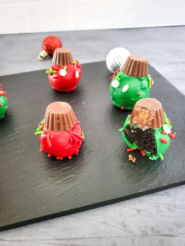 oreo christmas ornaments on a black tray. One has a bite out it