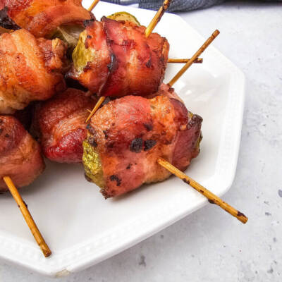 Air Fryer Bacon Wrapped Pickles on a white plate with a gray towel in the background