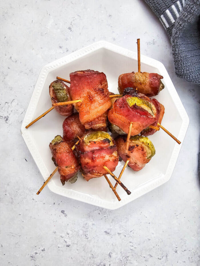 overhead shot of Bacon Wrapped Dilly Bites on a white plate with a gray towel in the background