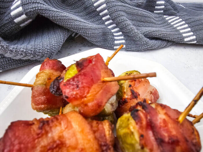 Bacon Wrapped Dilly Bites on a white plate with a gray towel in the background
