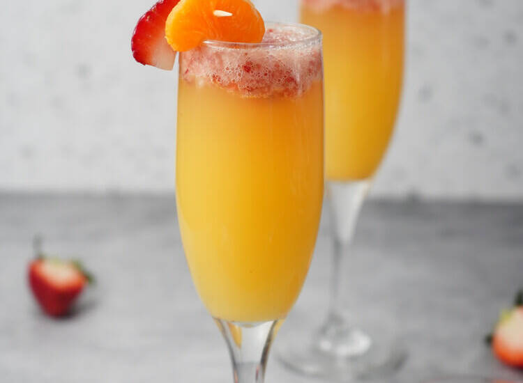 Strawberry Mimosas in glasses with orange slices and strawberry slices