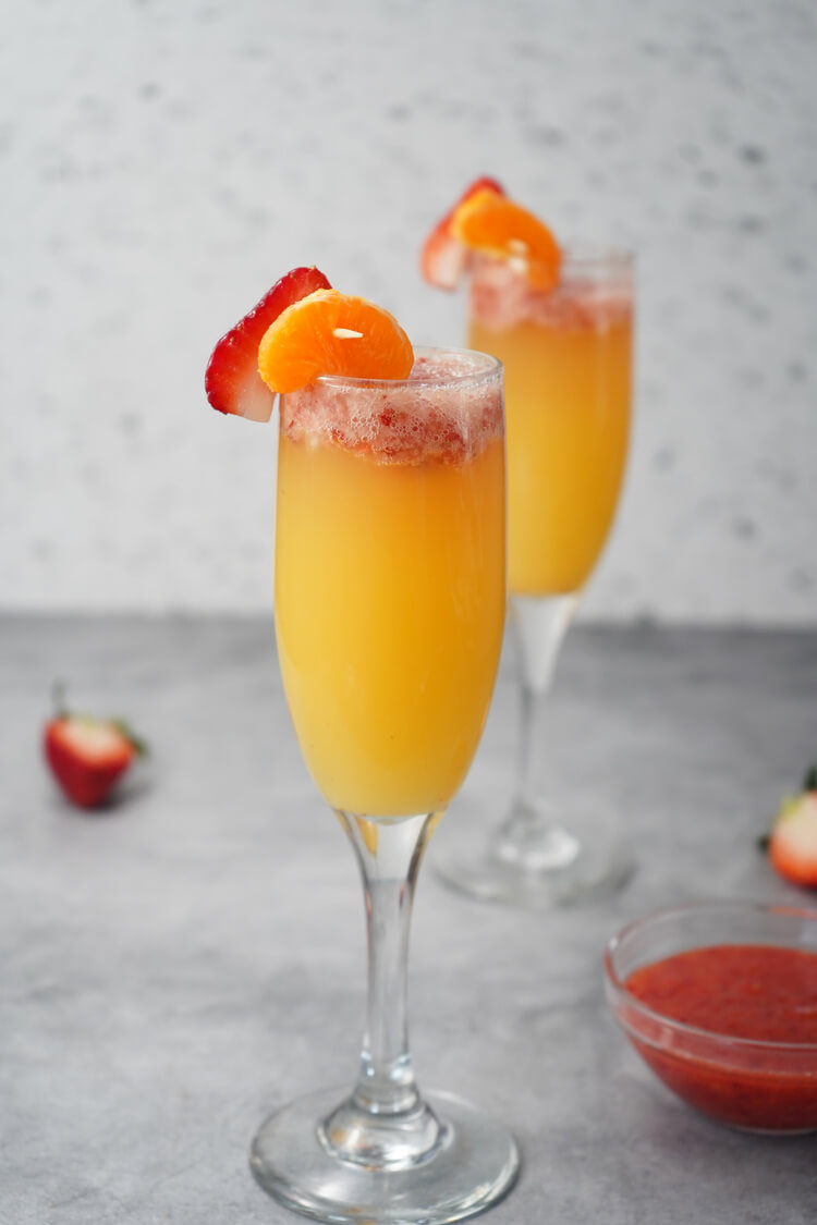 Strawberry Mimosas in glasses with orange slices and strawberry slices