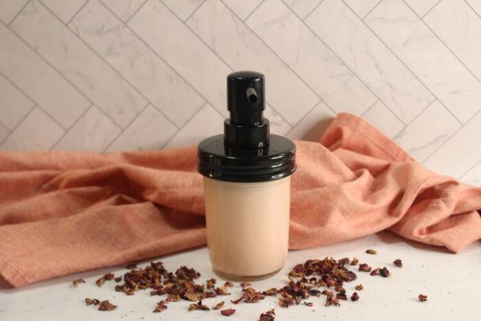DIY Rose Lotion in a glass bottle with rose petals