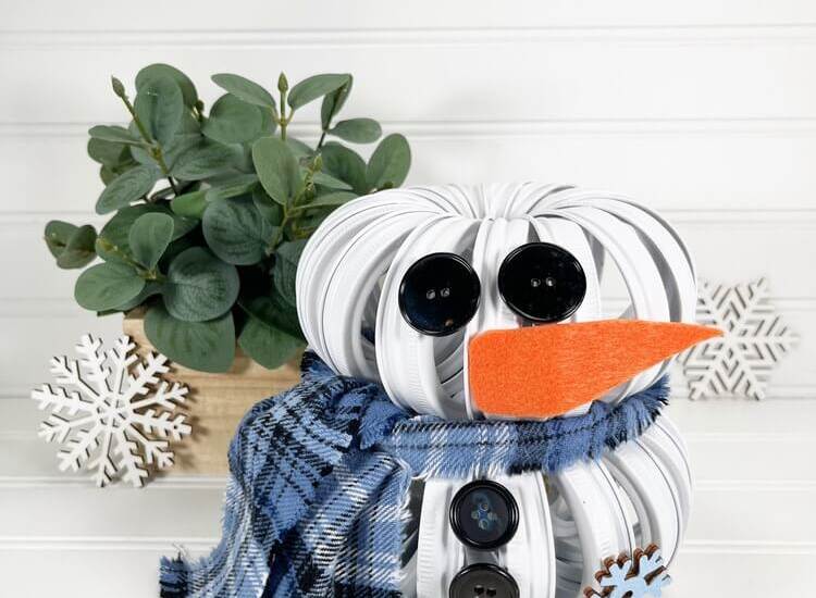 Mason Jar Lid Snowman DIY with a plant in the background