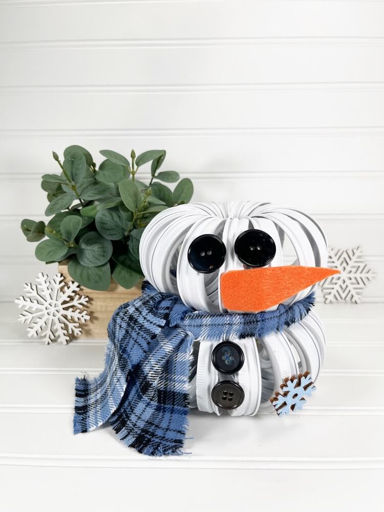 Mason Jar Lid Snowman DIY with a plant in the background