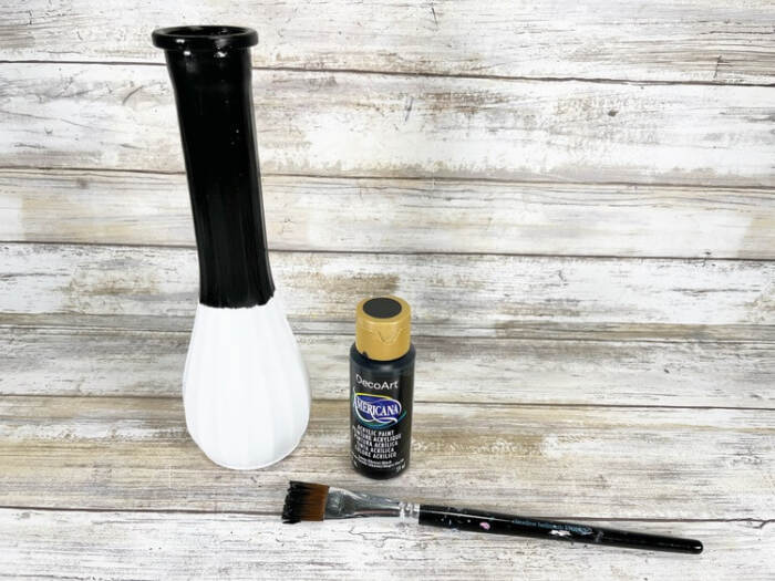 Glass vase painted white on the bottom and black on the top to form a snowman shape.