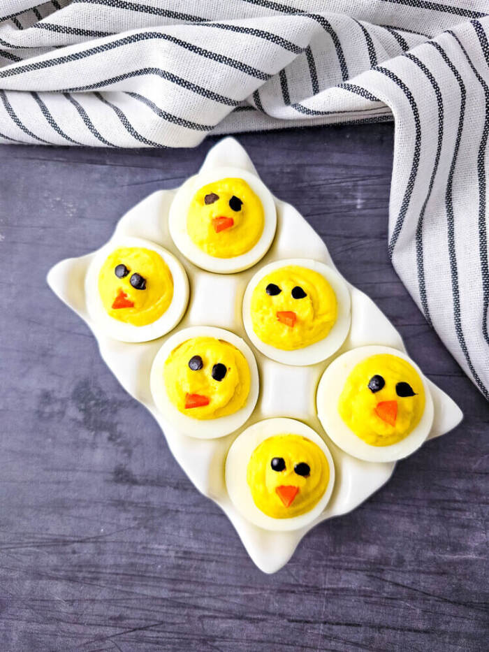 Easter Chick Deviled Eggs arranged on a white serving plate.