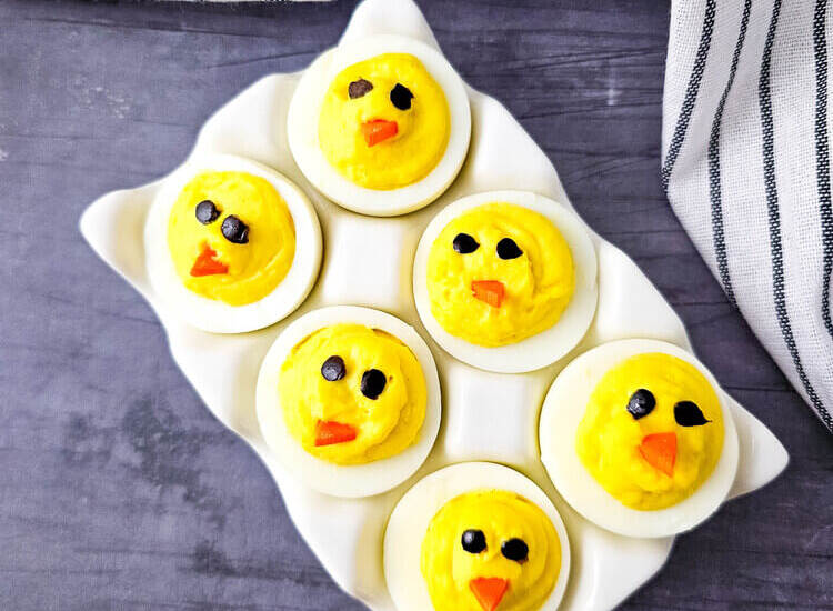 Easter Chick Deviled Eggs arranged on a white serving plate.