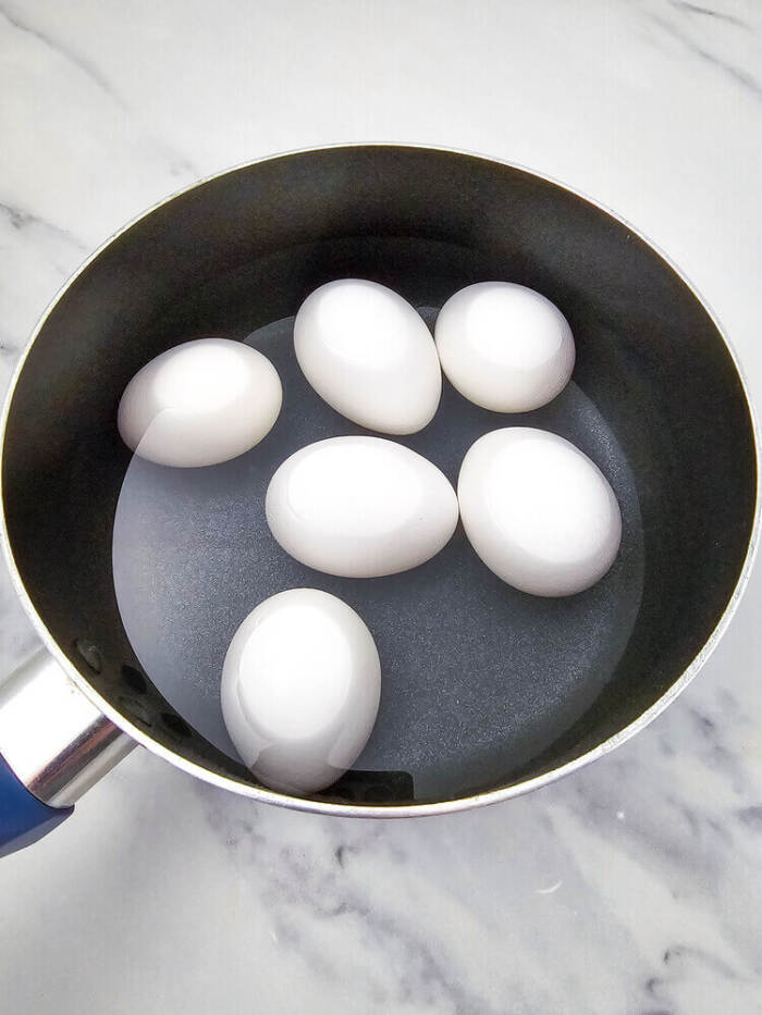 Hard-boiled eggs cooking in a pot for Easter Chick Deviled Eggs.