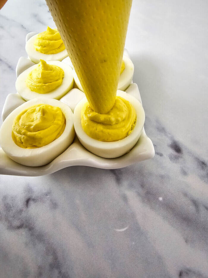 Deviled egg filling piped into egg whites for Easter Chick Deviled Eggs.