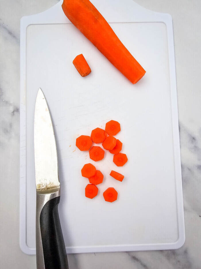 Carrots sliced on a cutting board for Easter Chick Deviled Eggs decorations.