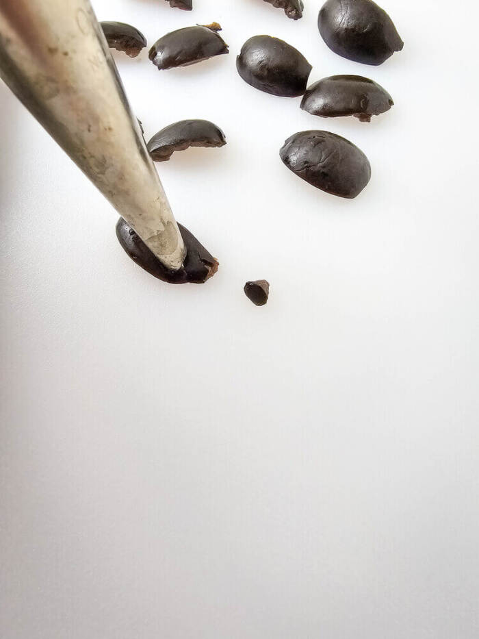 Black olives being cut into small pieces for Easter Chick Deviled Eggs eyes.