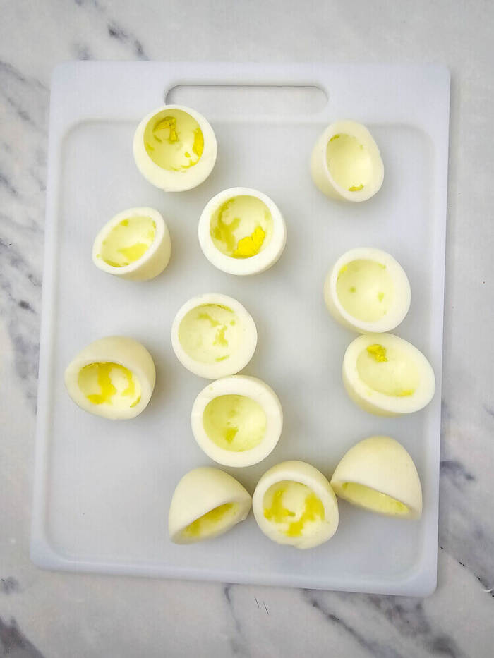 Egg white halves arranged on a cutting board for Easter Chick Deviled Eggs.