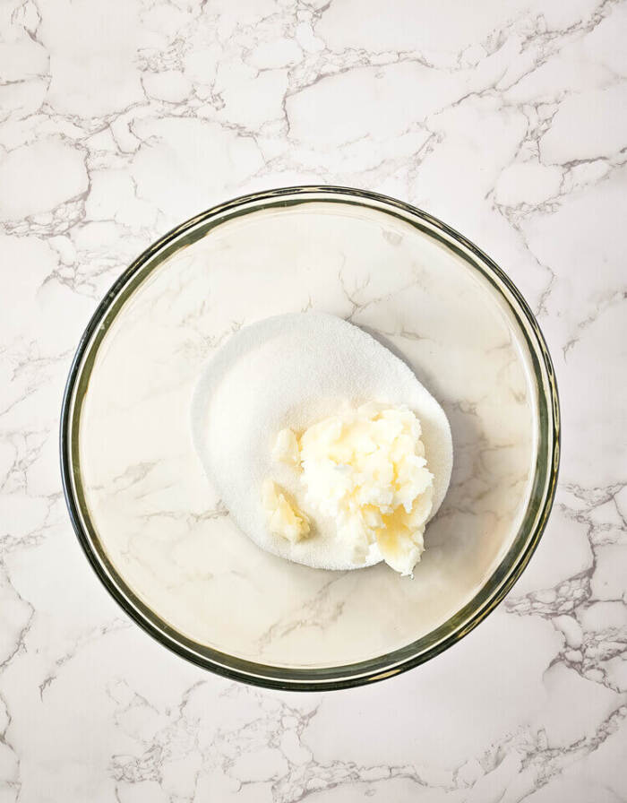 Sugar and butter in a glass mixing bowl.