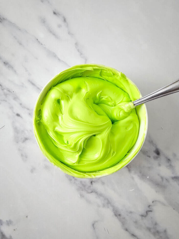 Green frosting in a white bowl