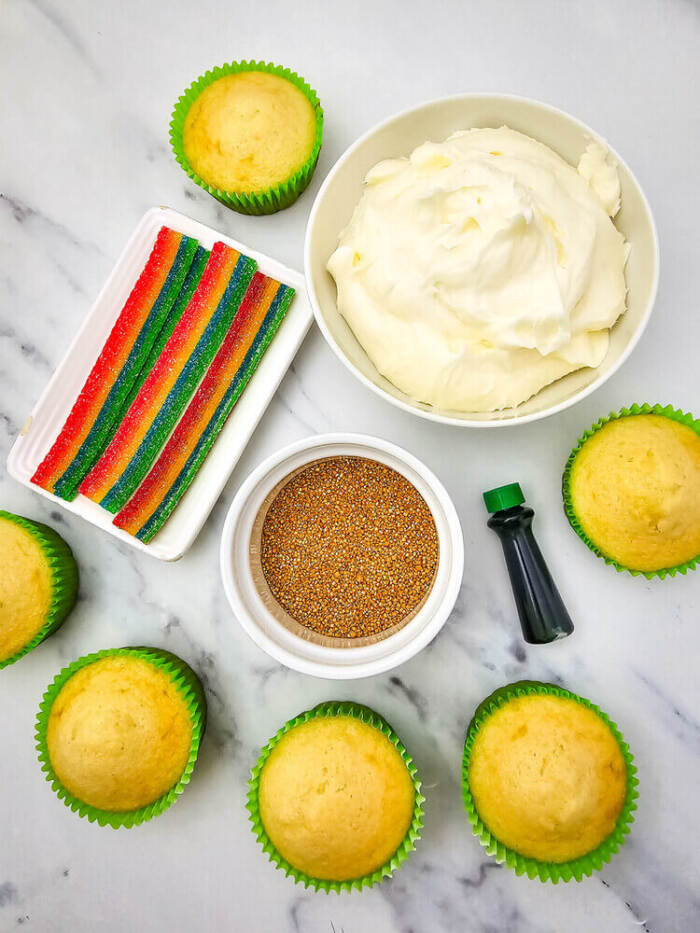 Ingredients laid out for St. Patrick’s Day rainbow candy cupcakes, including flour, eggs, milk, and candy.