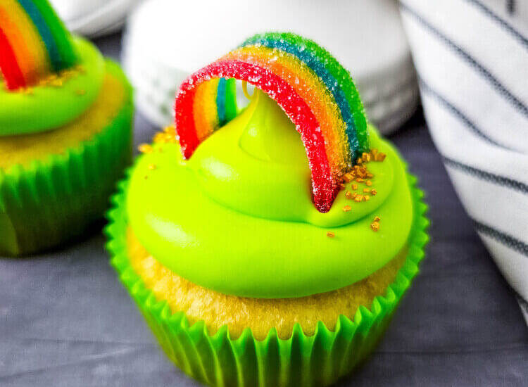St. Patrick’s Day cupcake with bright green frosting and a rainbow candy topper.