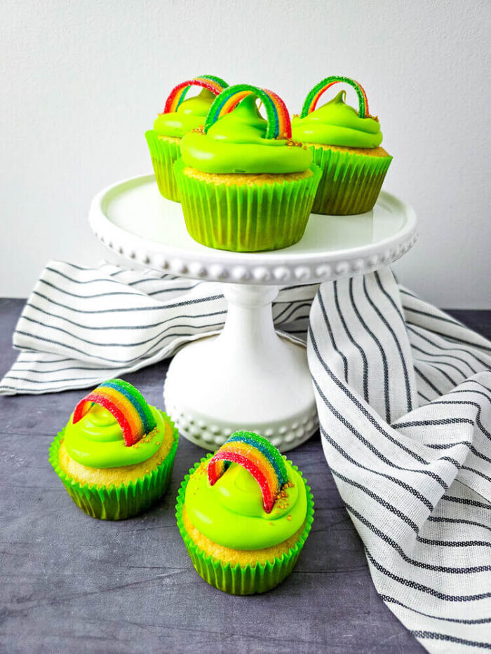 Rainbow candy St. Patrick’s Day cupcakes with white frosting and colorful candy rainbows.