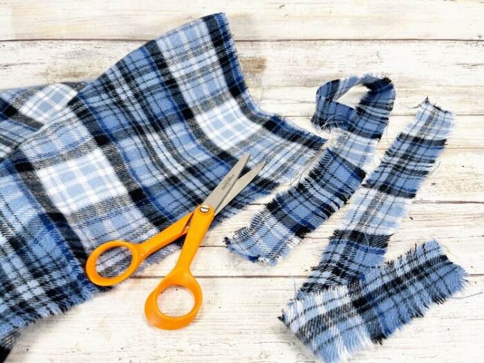 cutting blue plaid fabric scarf for snowman rope craft