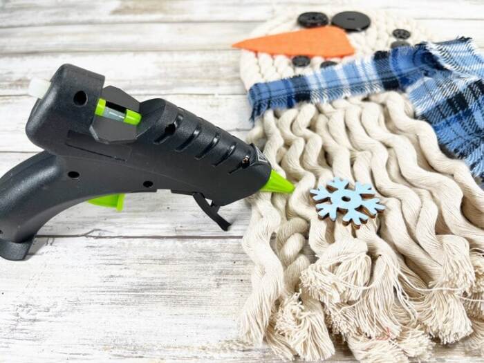 gluing painted snowflake onto rope snowman wall hanging