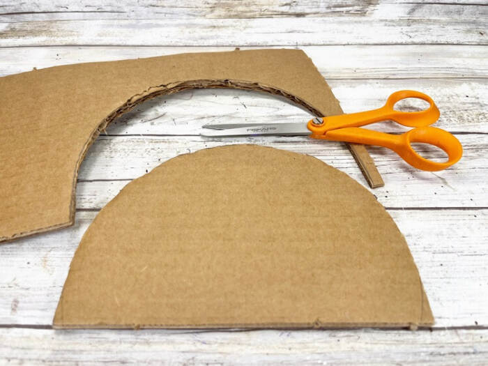 Cutting cardboard snowman base with scissors.