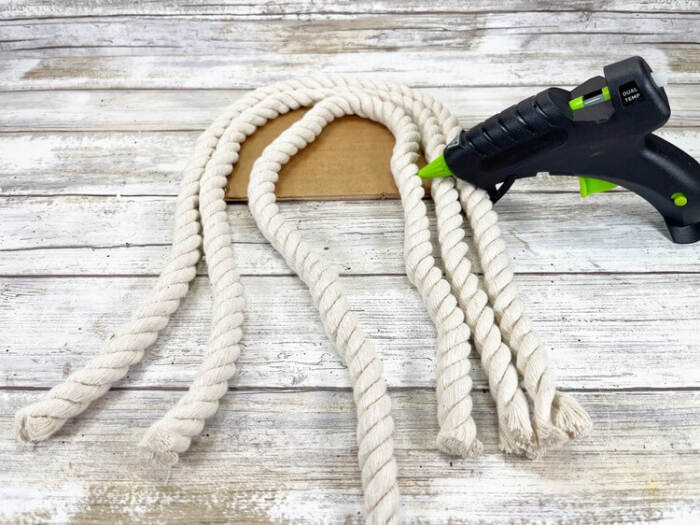Attaching rope strands to snowman body with glue gun.