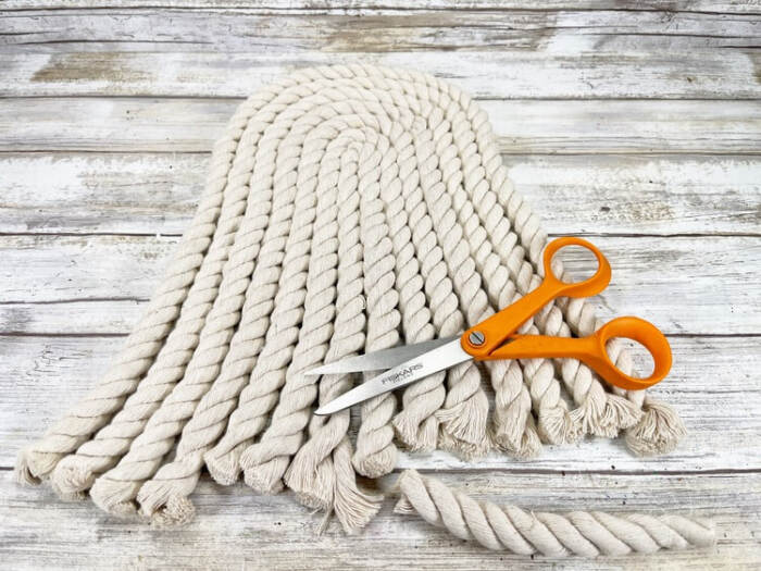 coiled cotton rope snowman body with scissors on wood background