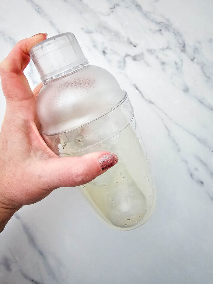 A hand shaking a shaker bottle for watermelon Jolly rancher drink.