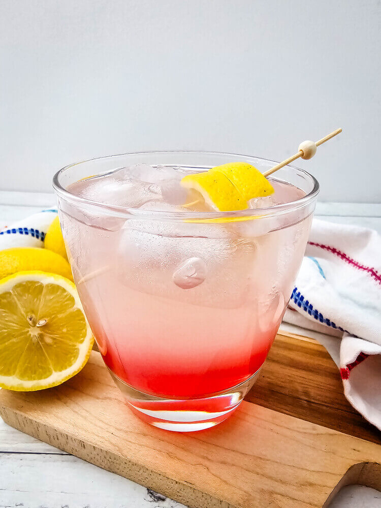 A glass of watermelon Jolly rancher drink on a chopping board.