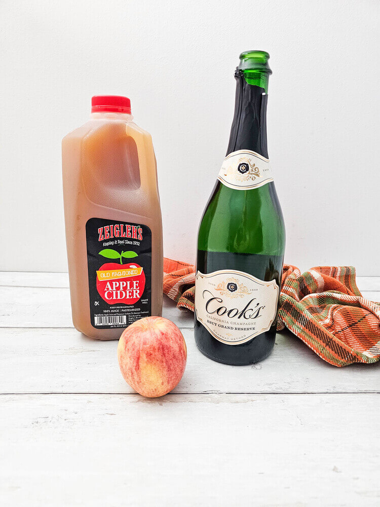 Ingredients for apple cider mimosas recipe on a wooden table.
