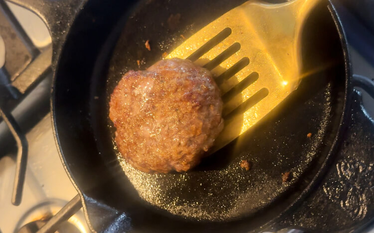 Cooked patty in a skillet for Copycat Applebee's O-M-Cheese Burger.