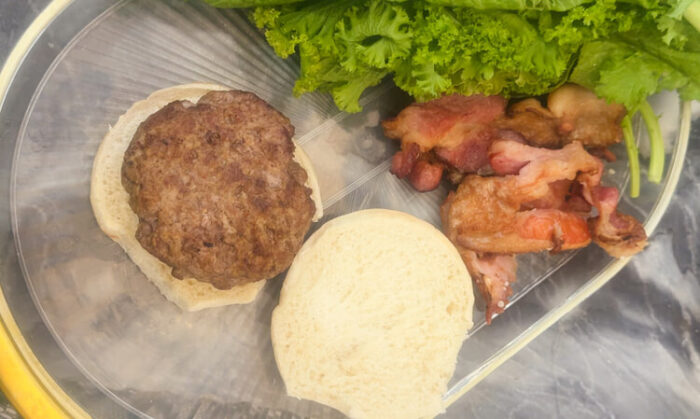 A bun and patty being assembled for Copycat Applebee's O-M-Cheese Burger.