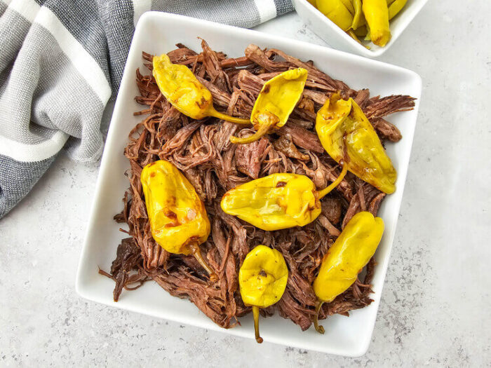 Dutch oven mississippi pot roast topped with peppers.