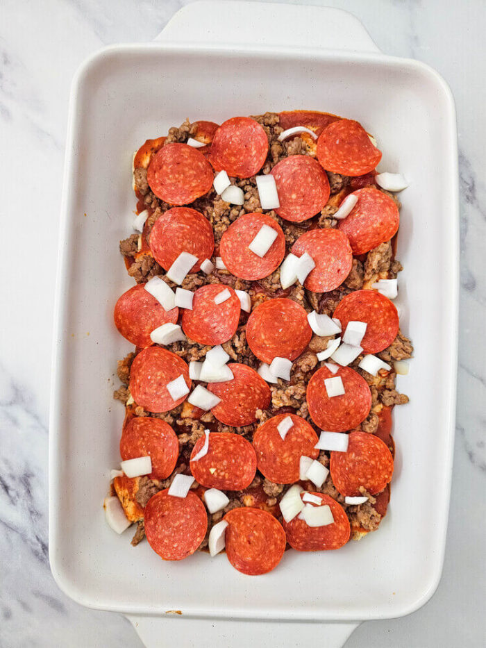 Biscuit pizza casserole in a dish garnished with chopped onions.